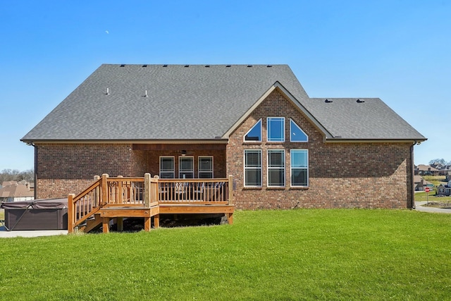 back of house featuring a deck, a yard, brick siding, and a hot tub