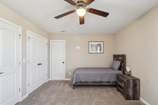 carpeted bedroom with a ceiling fan, visible vents, and baseboards