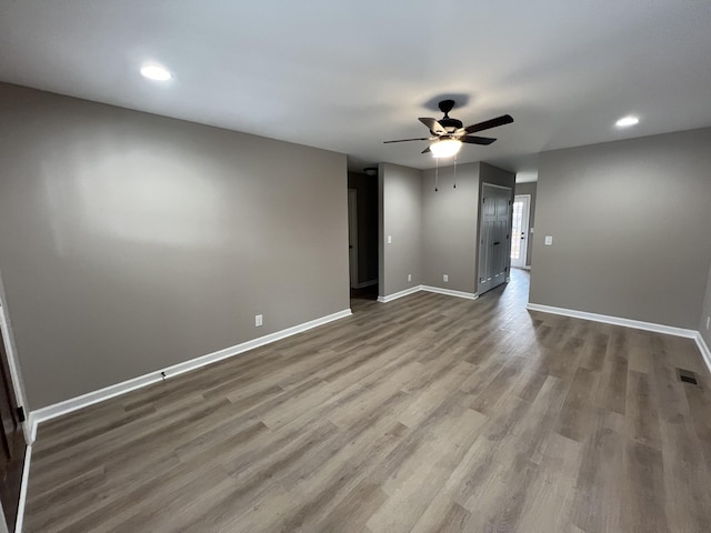 empty room with a ceiling fan, visible vents, baseboards, and wood finished floors