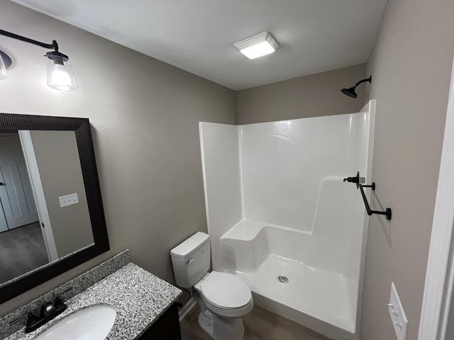 bathroom featuring toilet, a shower, and vanity