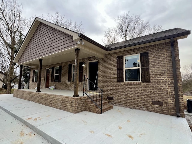 view of front of property featuring crawl space, covered porch, and brick siding