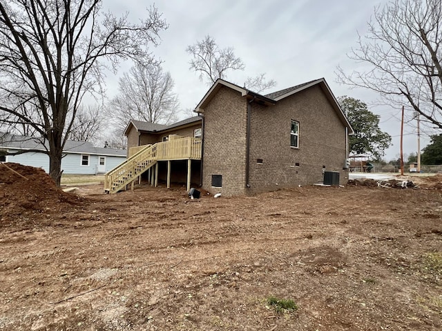 back of property with central AC unit, brick siding, crawl space, stairway, and a wooden deck