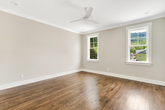 empty room with visible vents, baseboards, dark wood finished floors, a ceiling fan, and ornamental molding