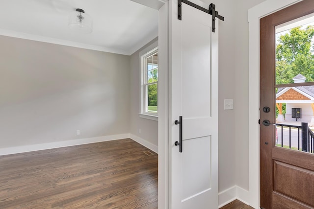 entryway featuring a barn door, crown molding, baseboards, and dark wood-type flooring