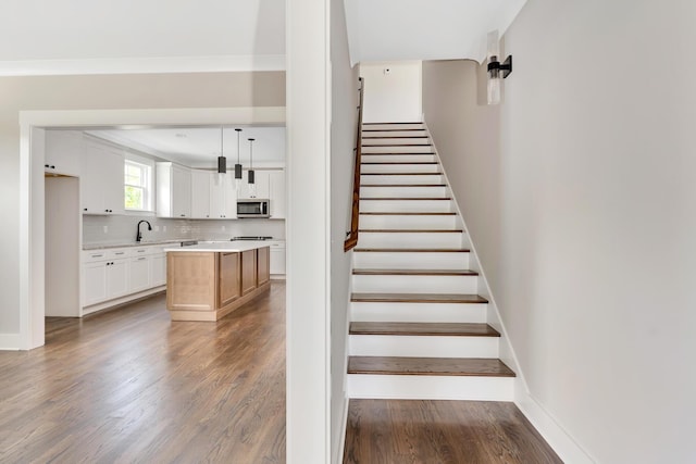 stairs with ornamental molding, baseboards, and wood finished floors