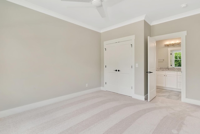 unfurnished bedroom featuring light carpet, baseboards, ceiling fan, ensuite bathroom, and crown molding