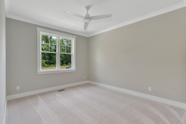 spare room featuring light carpet, ornamental molding, visible vents, and baseboards