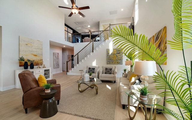 living area with visible vents, baseboards, stairway, a towering ceiling, and wood finished floors