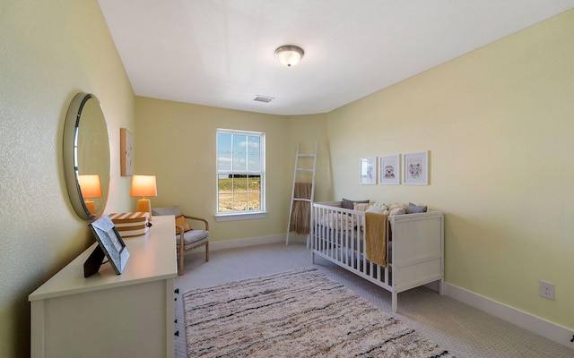 bedroom with a nursery area, carpet flooring, baseboards, and visible vents