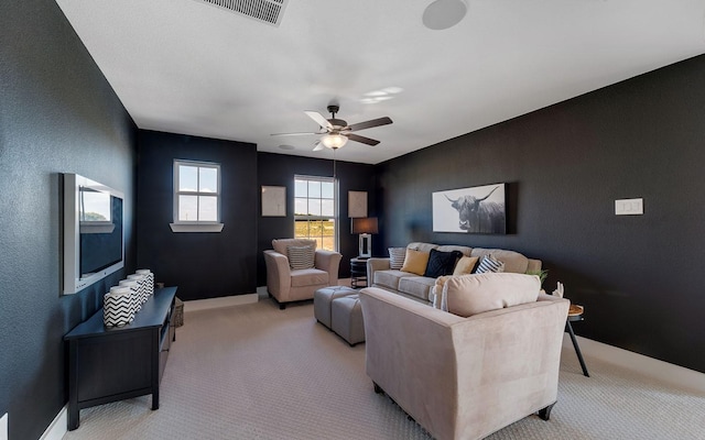 living area featuring visible vents, baseboards, light colored carpet, ceiling fan, and a textured wall