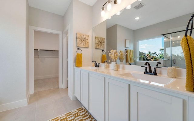 bathroom featuring visible vents, a stall shower, a sink, tile patterned flooring, and a spacious closet