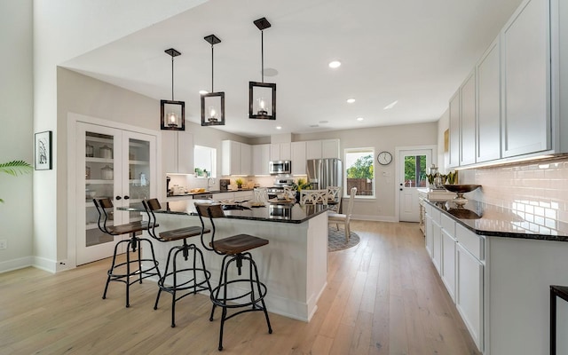 kitchen with light wood finished floors, backsplash, a kitchen island, a breakfast bar area, and stainless steel appliances