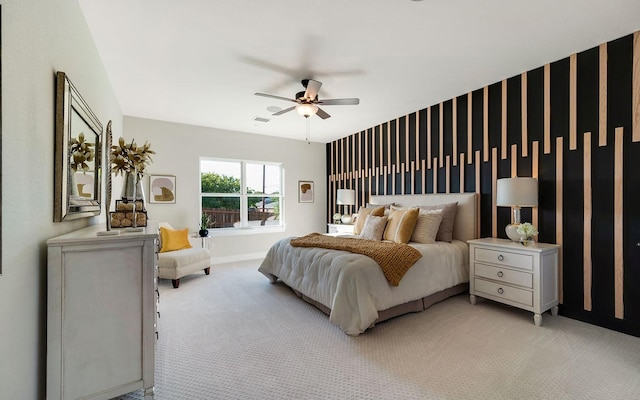 bedroom with visible vents, baseboards, light colored carpet, ceiling fan, and an accent wall