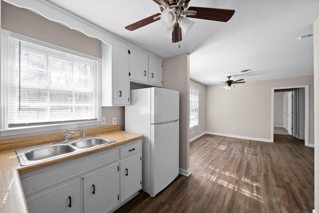 kitchen with a textured ceiling, dark wood-style flooring, a sink, and freestanding refrigerator