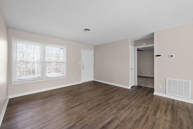 spare room with baseboards, visible vents, and dark wood-style flooring