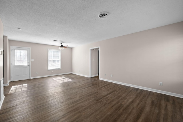 empty room featuring baseboards, visible vents, a ceiling fan, dark wood-style floors, and a textured ceiling