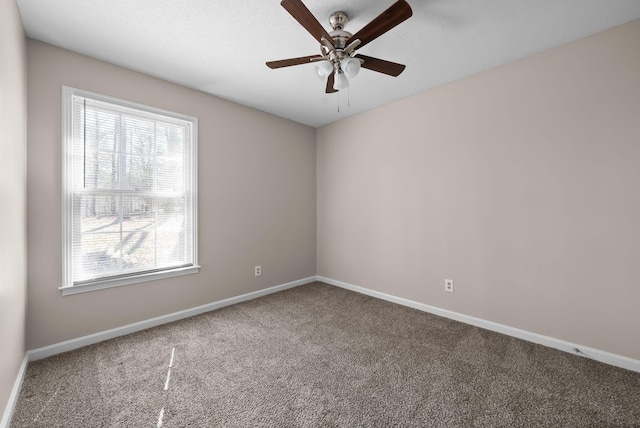 carpeted spare room with a ceiling fan and baseboards