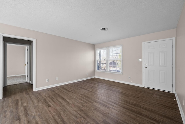 unfurnished living room featuring dark wood-type flooring, visible vents, and baseboards