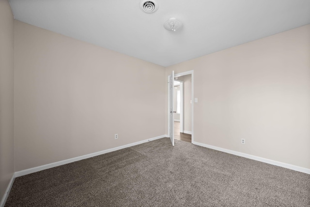 unfurnished room with carpet floors, visible vents, and baseboards