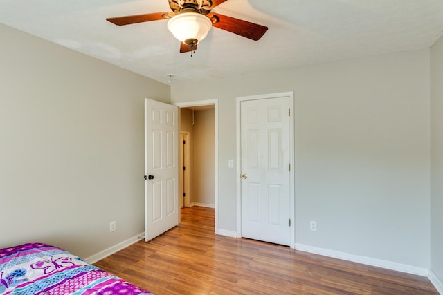 unfurnished bedroom featuring ceiling fan, light wood-style flooring, and baseboards