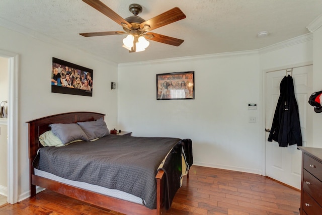 bedroom featuring a textured ceiling, wood finished floors, a ceiling fan, baseboards, and ornamental molding