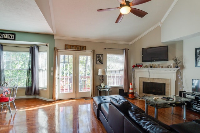 living room with lofted ceiling, wood finished floors, baseboards, ornamental molding, and a tiled fireplace