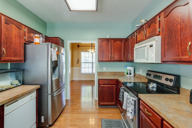 kitchen with light wood-style floors, baseboards, appliances with stainless steel finishes, and light countertops