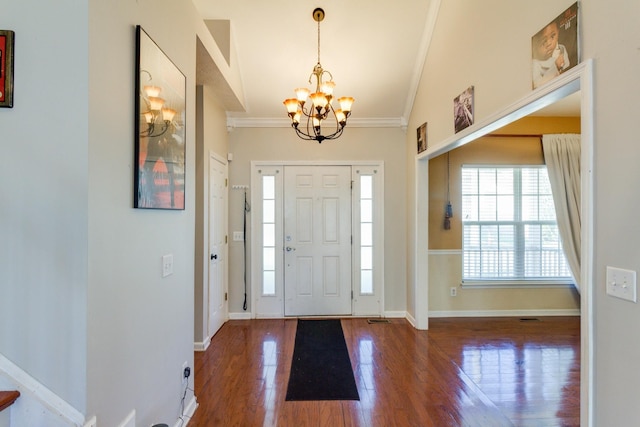 entryway featuring an inviting chandelier, baseboards, crown molding, and wood finished floors