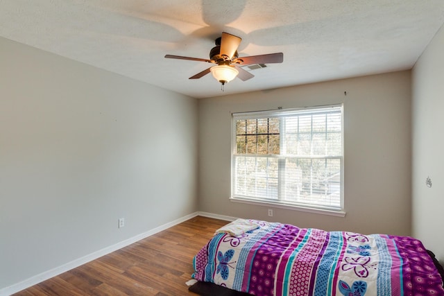 bedroom with visible vents, baseboards, ceiling fan, wood finished floors, and a textured ceiling