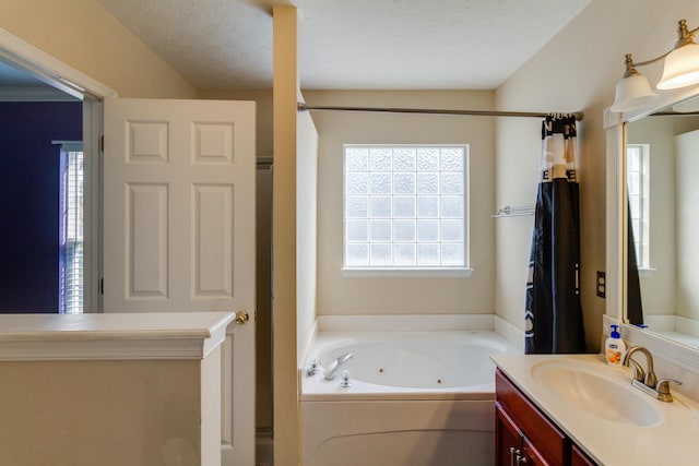 bathroom featuring a textured ceiling, a tub with jets, and vanity