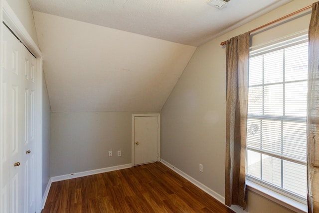 additional living space featuring visible vents, vaulted ceiling, baseboards, and wood finished floors