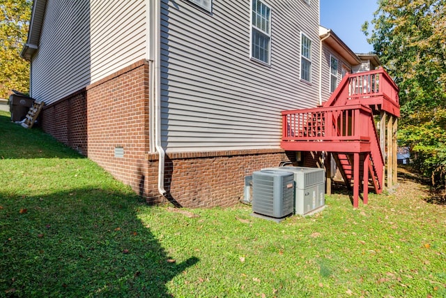 view of side of home featuring a lawn, stairway, a wooden deck, central air condition unit, and brick siding