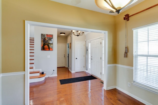 entryway featuring a notable chandelier, baseboards, and wood finished floors