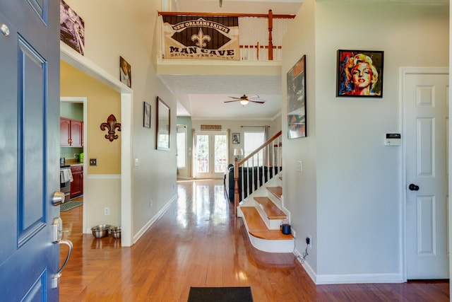 entrance foyer featuring stairs, a high ceiling, wood finished floors, and baseboards