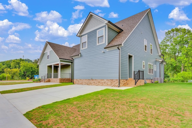 view of front of property with driveway, roof with shingles, and a front yard