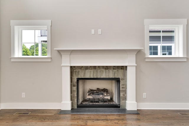 details featuring visible vents, a fireplace, baseboards, and wood finished floors