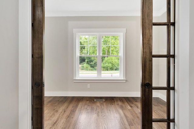 spare room with baseboards, visible vents, crown molding, and wood finished floors