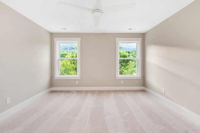 spare room featuring baseboards, a ceiling fan, and light colored carpet