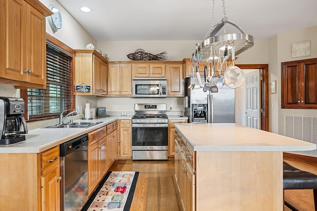 kitchen featuring stainless steel appliances, light wood finished floors, a sink, and light countertops