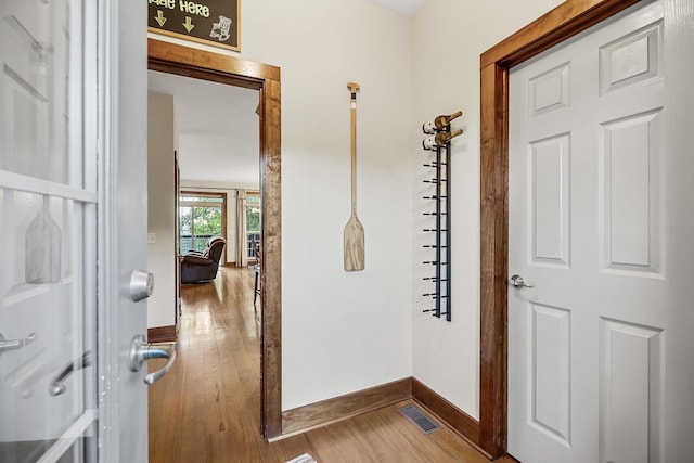 corridor with wood-type flooring, visible vents, and baseboards