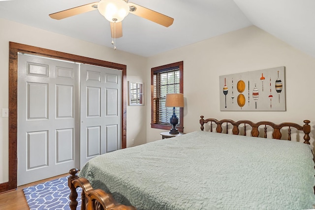 bedroom with a ceiling fan, lofted ceiling, a closet, and wood finished floors