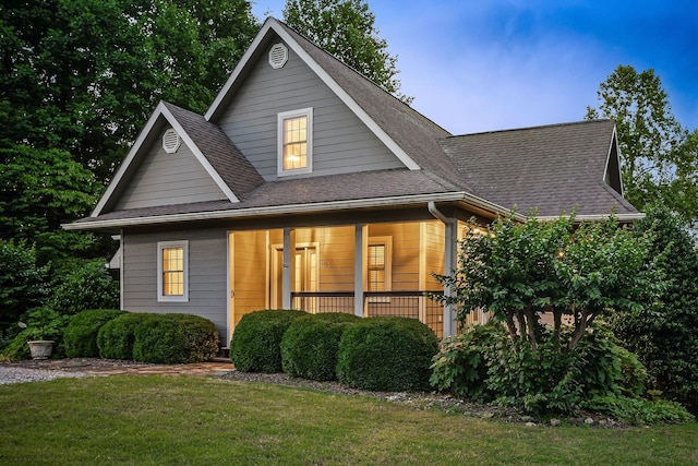 view of front of property featuring covered porch, roof with shingles, and a front yard