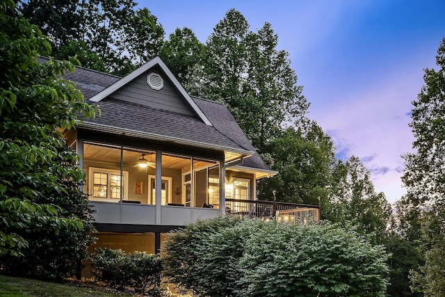 rear view of house featuring roof with shingles and a sunroom