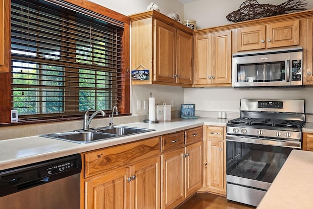 kitchen featuring dark wood-style floors, stainless steel appliances, a sink, and light countertops