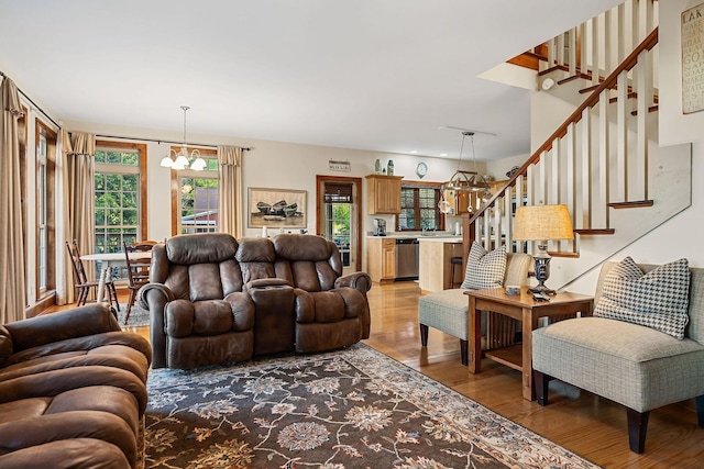 living area with light wood-style flooring, stairway, and a notable chandelier