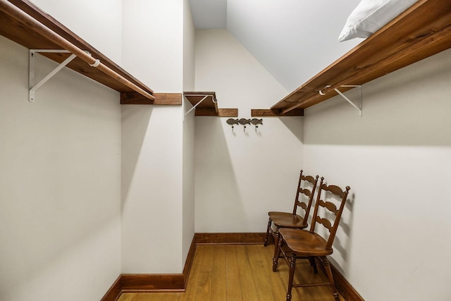 walk in closet with vaulted ceiling and hardwood / wood-style floors