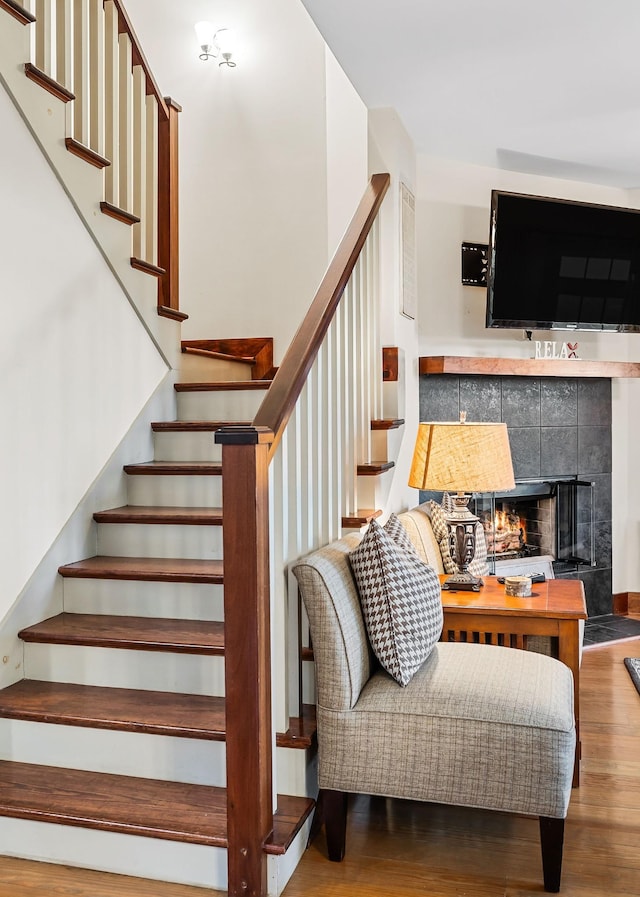 staircase featuring a fireplace and wood finished floors