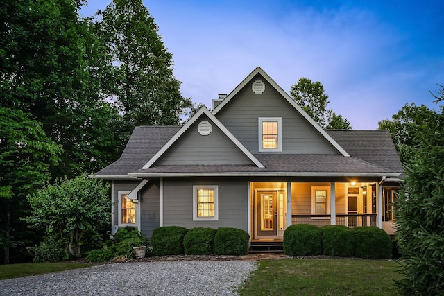 view of front of house featuring covered porch, a shingled roof, and a chimney