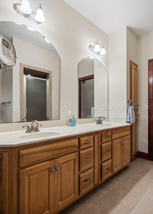 bathroom featuring double vanity, a shower stall, a sink, and tile patterned floors