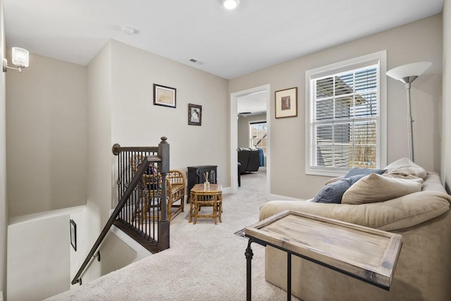 living area with an upstairs landing, visible vents, baseboards, and carpet